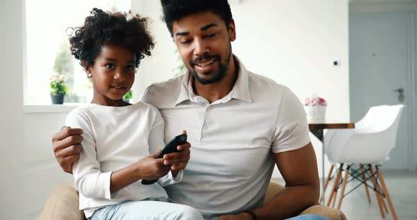 Father and Daughter Sitting on Couch at Home