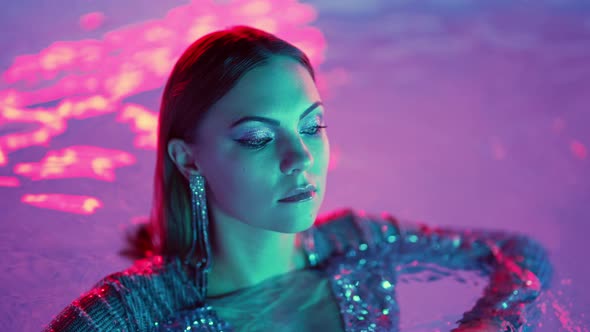 Beautiful Woman Posing in Pool Water Under Neon Color Light