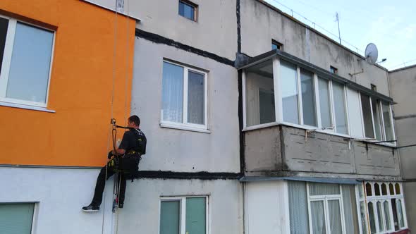 Painting and Decorating Buildings. Worker on a Construction Site of a High-rise Building. Dangerous