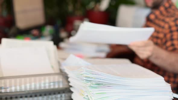 A Man Parses Papers in the Office and Stacks Them in a Pile. Focus on a Stack of Papers.