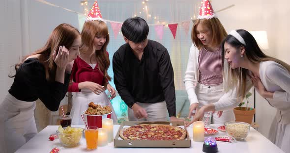 Slow motion of Happy young Asian friends enjoying pizza in night party.