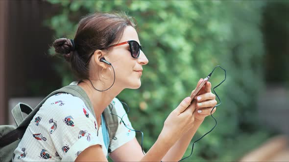 Young Beautiful Woman Listening to the Music Dancing and Singing in the Park