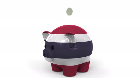 Coins Fall Into Piggy Bank Painted with Flag of Thailand alt