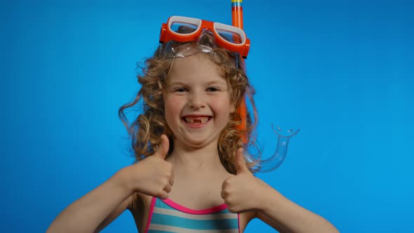 Little Girl with Swimming Mask and Snorkel is Showing Two Big Thumbs in Studio