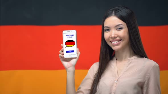 Nice Woman Holding Phone With Language Study App, German Flag on Background