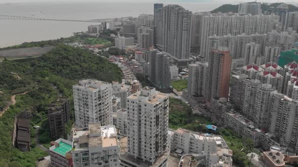 Pan and tilt reveal starting from Taipa apartments to Macau skyline over mountain in Taipa