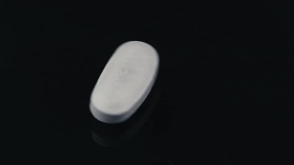 White Cardiac Pill Spinning on a Black Mirror Surface