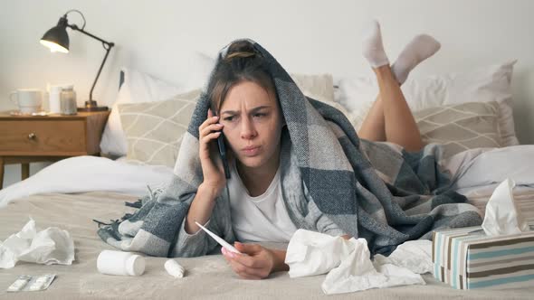 Sick Woman Wrapped in Blanket Plaid Lying on Bed Holding Thermometer and Calling Family Doctor