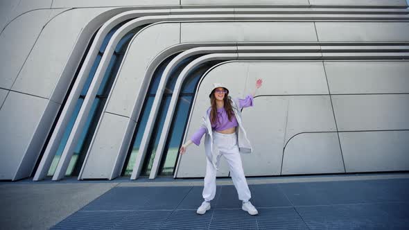 Fashion Cutte Woman with Sunglasses and Hat Dancing Outside Looking at Camera