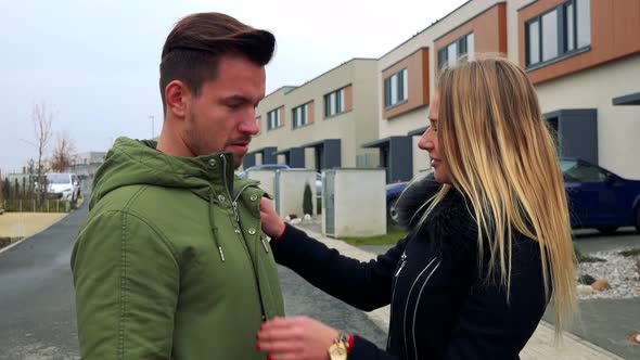 A Woman Adjusts a Man's Clothes on an Empty Street