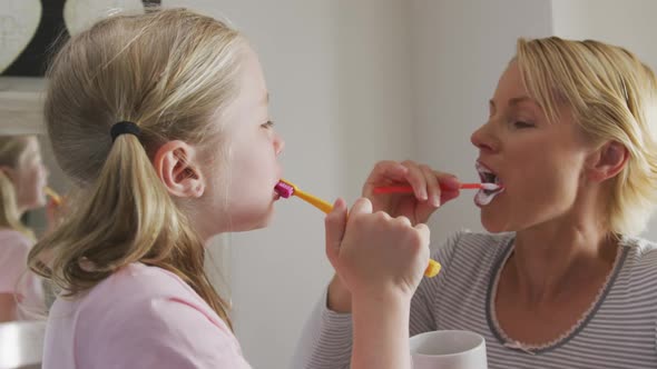 Side view of Caucasian woman and her daughter brushing their teeth