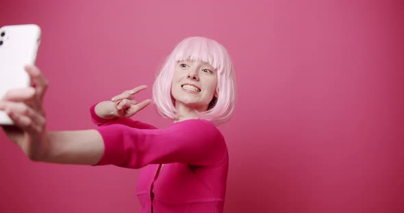 Young Nice Woman with Pink Hair Taking Photos Self on Isolated Pink Background