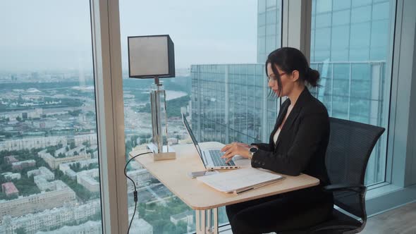 Business Woman Works in a Modern Office Located on a High Floor of a Skyscraper. Attractive Girl