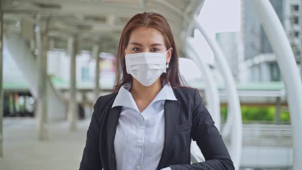 Young Asian office business woman standing outdoor in city and put on face mask due to Covid19.