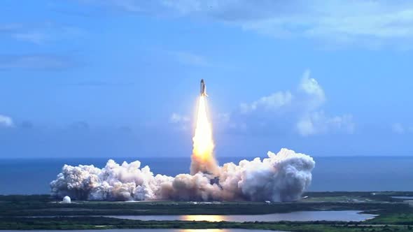 Space Shuttle Lifting Off over the water.