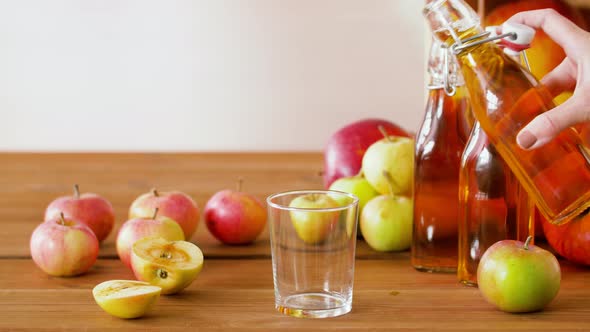 Hand Pouring Apple Juice From Bottle To Glass