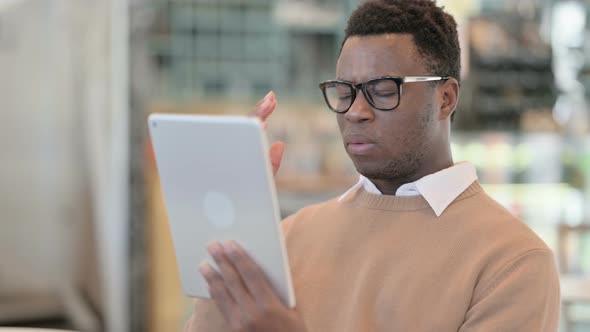 Creative African Man Having Loss on Tablet in Cafe