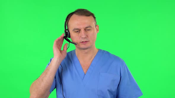 Medical Man Talking on Headphones at Support Service, Green Screen