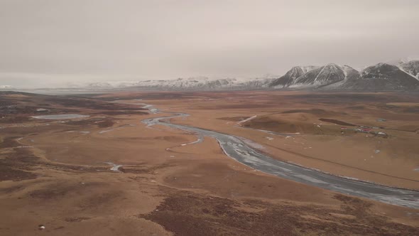 Stunning aerial drone shot of beautiful landscape in iceland. Frozen river, grass land and mountains