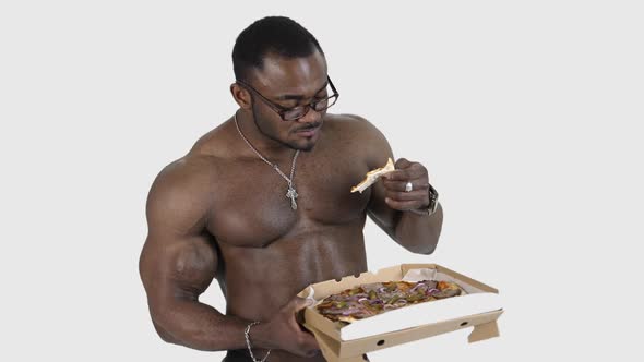 Fit young african man with beautiful torso eating pizza