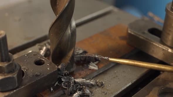 A Large Diameter Drill Bit Drills a Metal Plate and Metal Chips are Formed