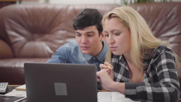 Young Couple Sitting in Front of a Laptop at Home