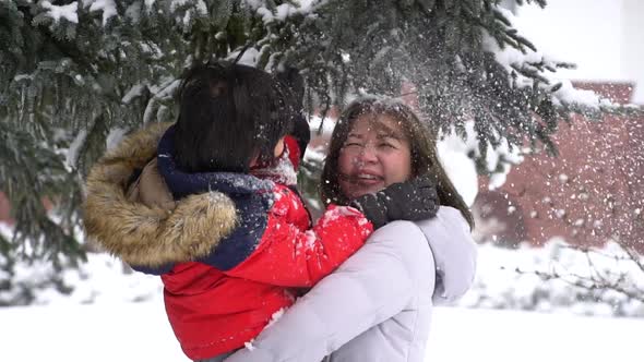 Asian Mother And Son Enjoying Snowy Winter Day Outdoors
