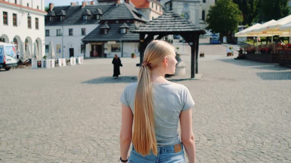 Back View of Pretty Blonde Woman Walking on the Street in Summer