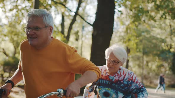 Senior Couple Riding Double Bicycle in Autumn. Grandmother and Grandfather Cycling Together