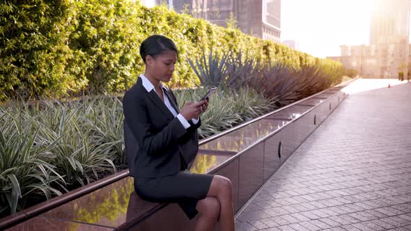 Mixed ethnicity business woman works on her phone