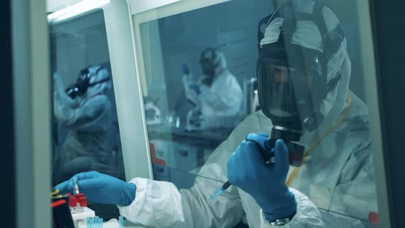 Researcher in a Hazmat Suit Is Analyzing Biological Samples. Medical Research of Antibodies To COVID