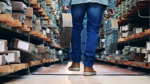 A Man Is Walking Along the Archive with Film Reels in Cases