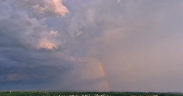 There is a Bright Rainbow in the Sky During a Severe Thunderstorm Against the Backdrop of the