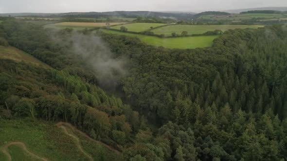 Aerial shot of foggy woodland deep in the countryside, low hanging mists