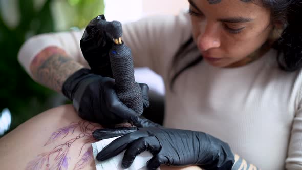 Crop artist drawing tattoo on body of client in shop