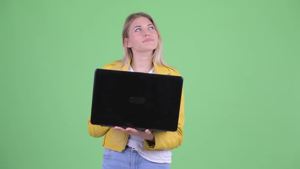 Happy Young Rebellious Blonde Woman Thinking While Using Laptop