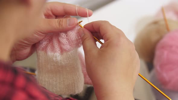 Hands of a Woman Knits a Piece of Clothing From a Thin Yarn