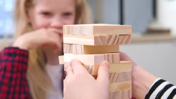 Children Playing Wooden Block Removal Tower Game at Home
