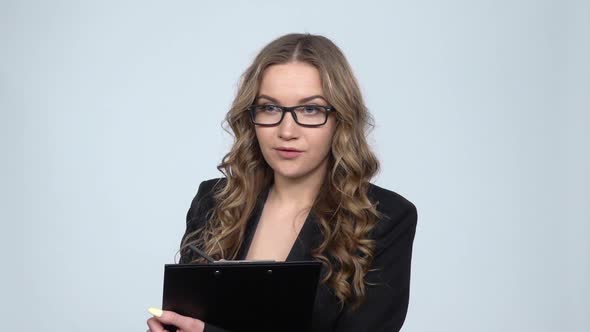 Female Office Worker Holding Clipboard Looks Around and Makes Notes, Slow Motion