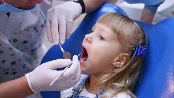 Little girl at the dental office. Male dentist examines child's mouth.