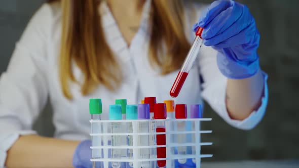 Blood sample tubes. Doctor hand taking a blood sample tube from a rack with machines of analysis