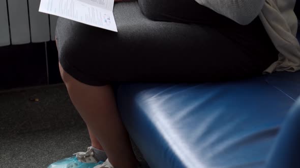 Young Pregnant Woman In Medicine Protective Mask Reading On Couch Waiting For Appointment Medical