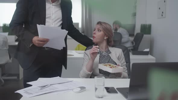 Woman Eat at the Office, Man Gives Her Documents