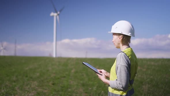 Woman  Standing Near Wind Mill and Checking Information on Table