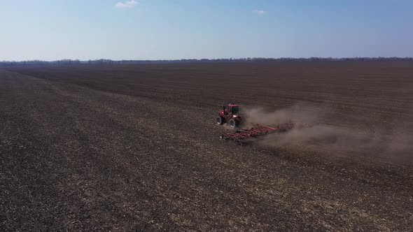 Red Tractor Working in Field at Springtime Aerial View