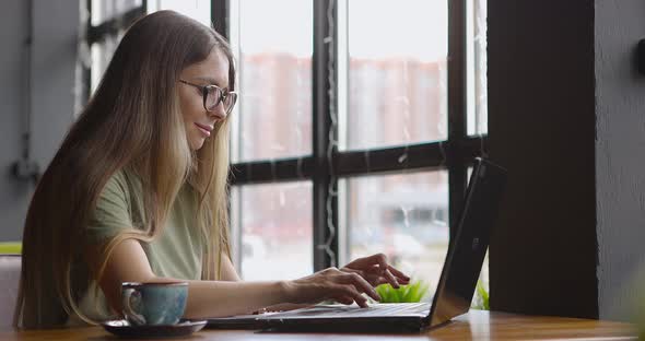 Woman Working Remotely and Drinking Coffee in Cafe