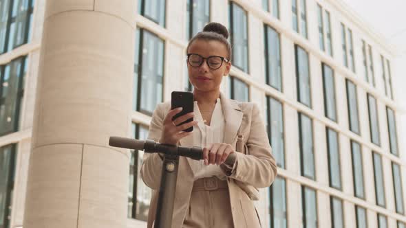 Businesswoman with Kick Scooter and Smartphone Outdoors