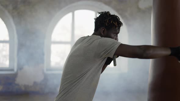 Boxer Practicing Shadow Boxing in Foggy Sport Studio with Weights