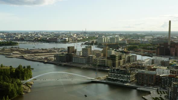 Aerial, pan, drone shot overlooking a bridge, the Kalasatama and Sompasaari cityscape, on a sunny ev