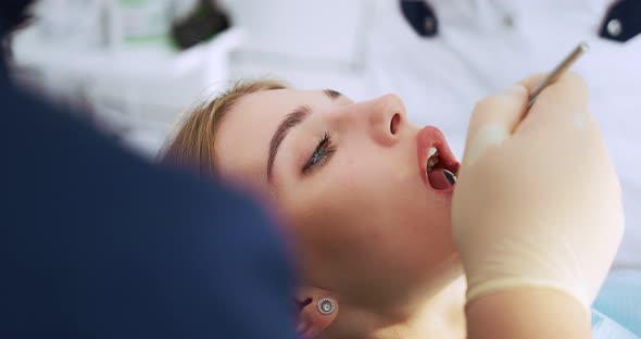 The Dentist Performs an Examination Using a Dental Mirror a Woman